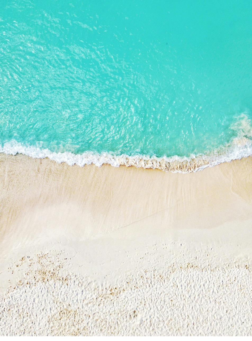 Shoreline from above, white sand meeting turquoise water