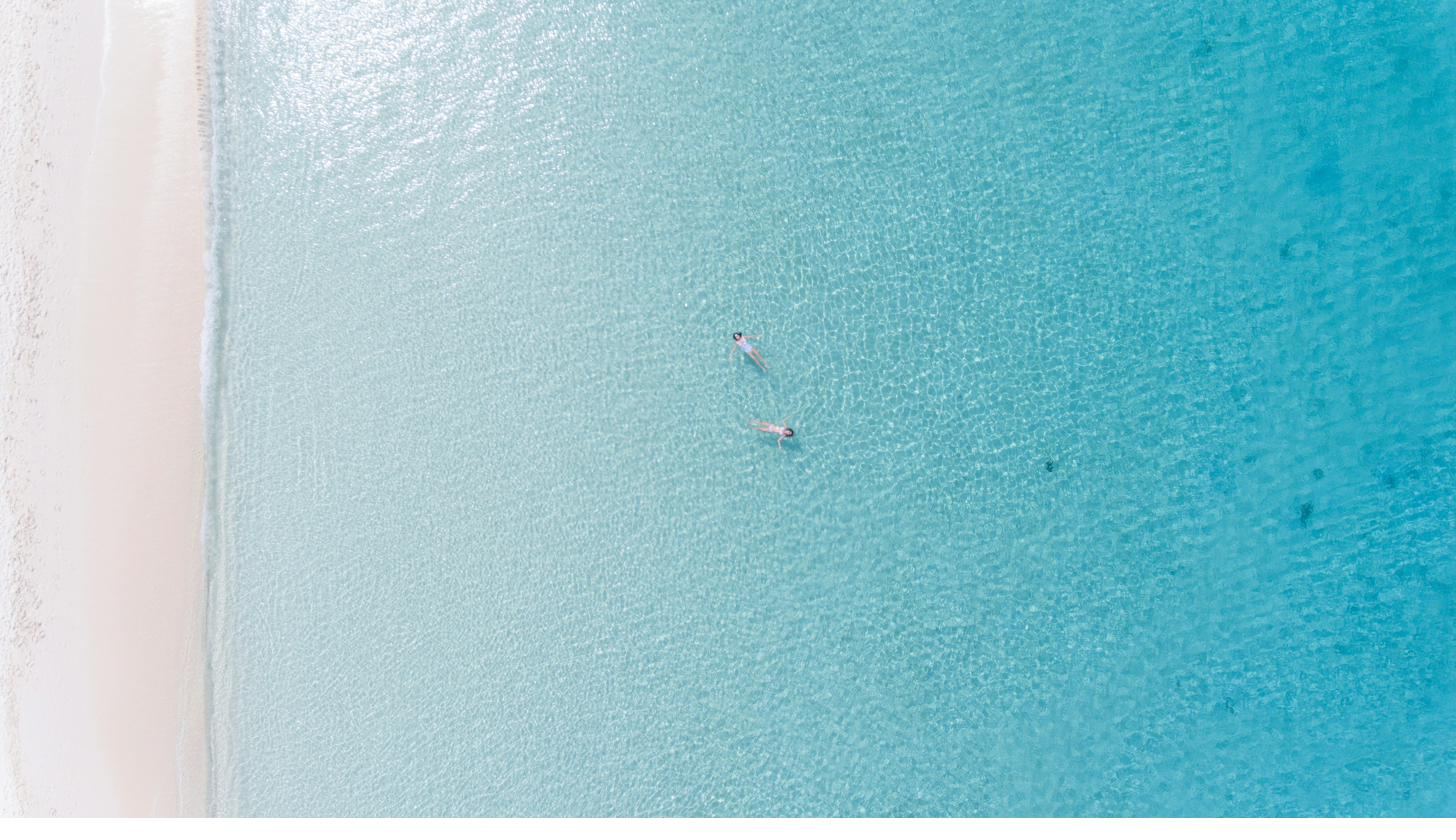 Aerial view of two swimmers in clear turquoise water